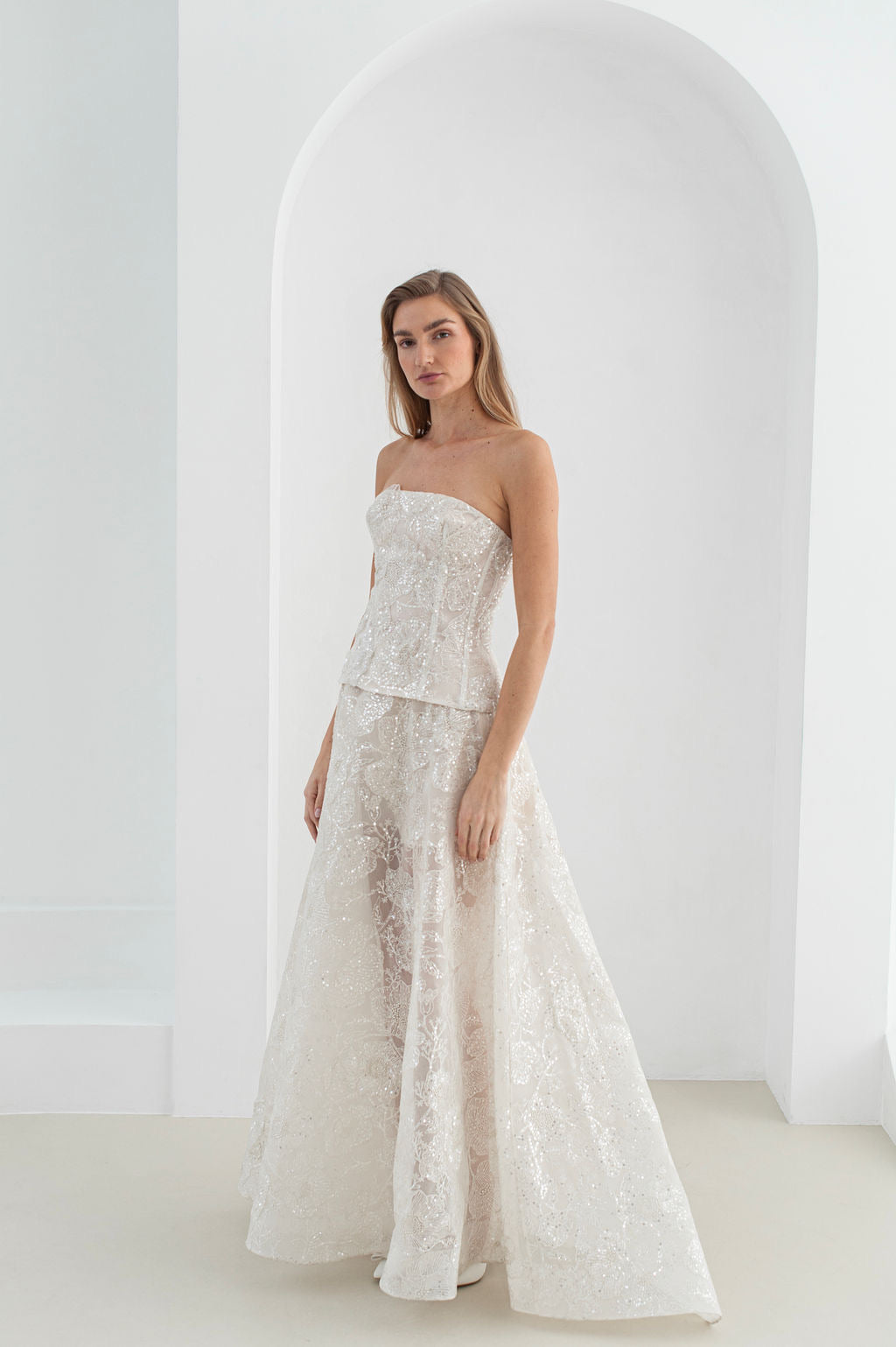 Handmade long bridal gown with hand-stitched floral appliqués, voluminous flowing skirt, and optional mini lace skirt for versatile evening wear