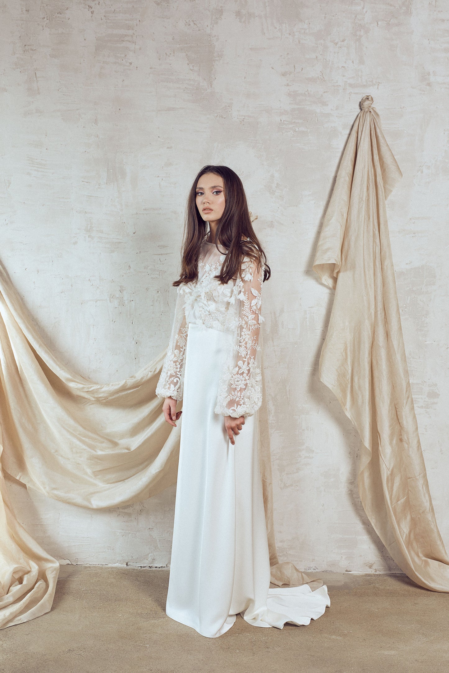 Long sleeve lace wedding dress with 3D floral detailing and flowing train for modern bridal look.