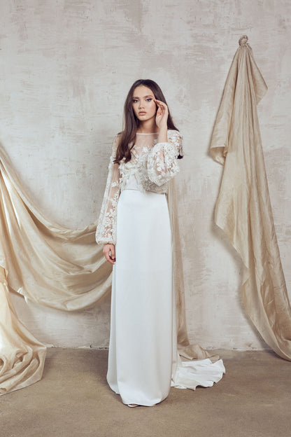 Long sleeve lace wedding dress with 3D floral detailing and flowing train for modern bridal look.